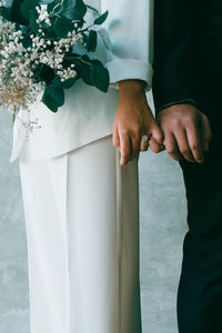 Midsection of man and woman standing against white wall