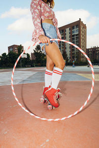 Woman wearing roller skates holding hoop at sports court
