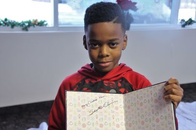 Portrait of smiling boy holding book at home