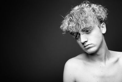 Portrait of shirtless boy against black background