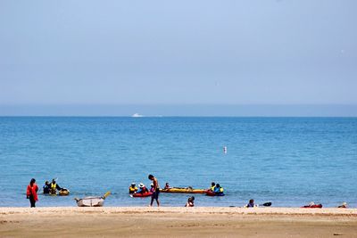 People at beach against clear sky