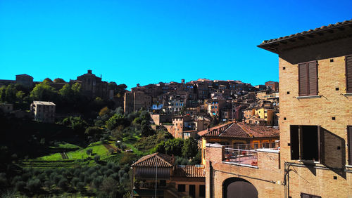 Buildings in city against clear blue sky