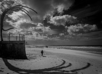 Scenic view of beach against cloudy sky