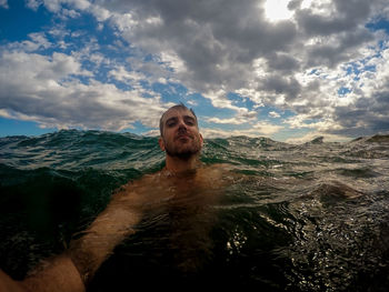 Portrait of man swimming in sea against sky