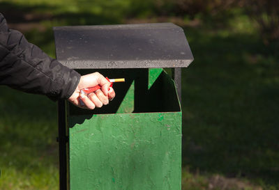 Close-up of man throwing cigarette in garbage bin