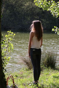 Rear view of woman standing at lakeshore