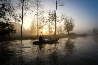 Silhouette man on boat against sky during sunset