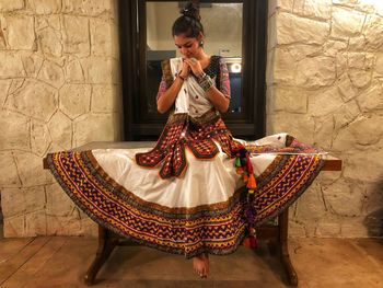 Woman in traditional clothing sitting on table