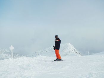 Man skiing on snowcapped mountain against sky