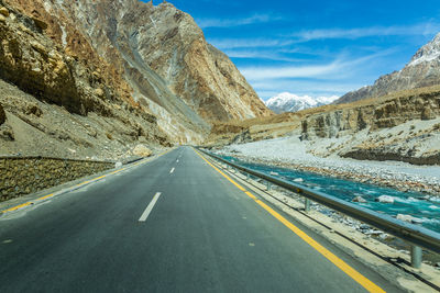 Empty road by mountains against sky