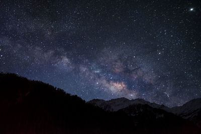 Scenic view of silhouette mountains against star field at night