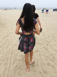 Rear view of woman walking on sand at beach