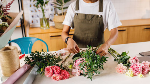 Midsection of florist standing by flowers on table