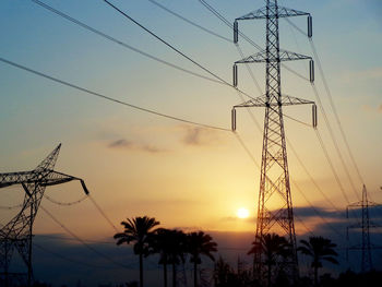 Low angle view of silhouette electricity pylon against sky