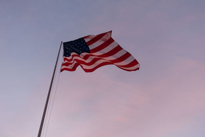 Low angle view of american flag waving against sky during sunset