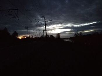 Silhouette electricity pylon against sky during sunset