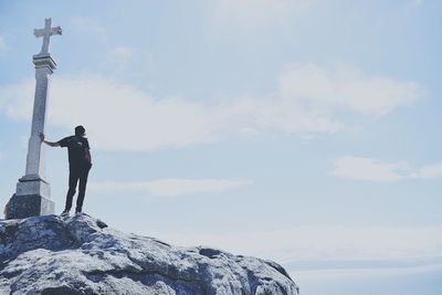 Man standing on rock against sky