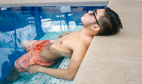 Side view of young man swimming in pool