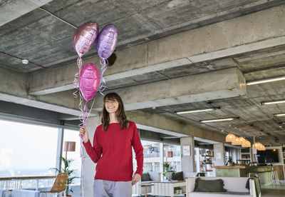 Portrait of woman with umbrella standing against ceiling