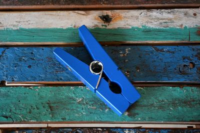 Close-up high angle view of wooden blue oversized clothespin on blue and teal wood boards