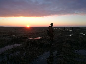 Man standing on beach against sky during sunset