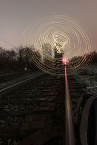 Light trails on railroad track against sky at night