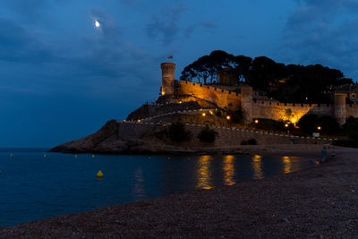 The medieval castle in tossa de mar, spain, offers a breathtaking view of the beach and sea at night