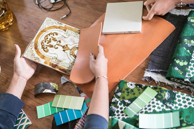 Cropped hands of female design professionals working at table in home office