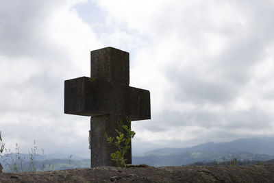 Cross on land against sky