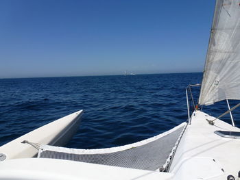 Sailboat sailing in sea against clear blue sky