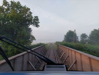 Bridge over railroad track in forest against sky
