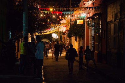 People walking on illuminated street at night