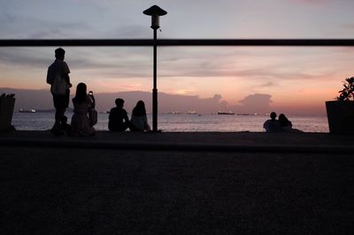 Silhouette people on beach against sky during sunset
