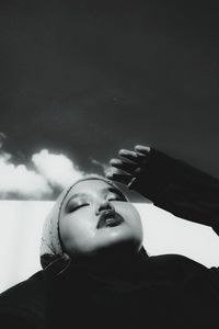 Low angle view of young woman looking up against sky