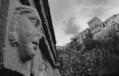 Low angle view of statue by building against sky