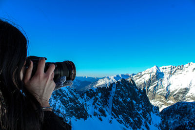 Midsection of snowcapped mountain against blue sky