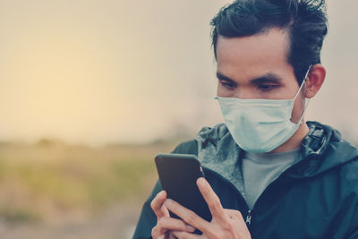 Portrait of young man using smart phone against sky