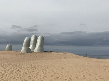 Scenic view of beach against cloudy sky