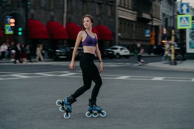 Full length of man skateboarding on street in city