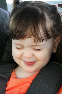 Close-up of cute girl with closed eyes wearing seat belt in car