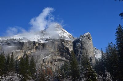 Low angle view of snow covered mountain against blue sky