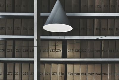 Illuminated lamp against books in library