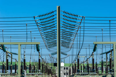 Low angle view of electricity pylon against blue sky