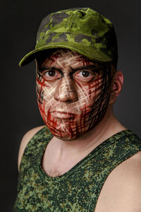 Portrait of soldier with camouflage make-up against black background