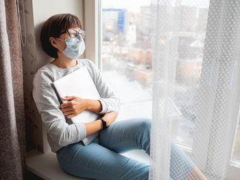 Woman in medical mask had lost her job. closed laptop. lockdown quarantine, coronavirus covid19. 