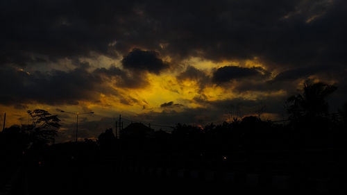 Silhouette trees against dramatic sky during sunset