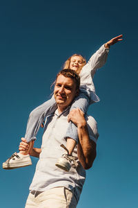 Low angle view of smiling young woman against clear blue sky