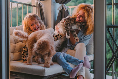 Happy child with smile plays on summer at home with mom, dog at sunset. cat, dog, pets family member