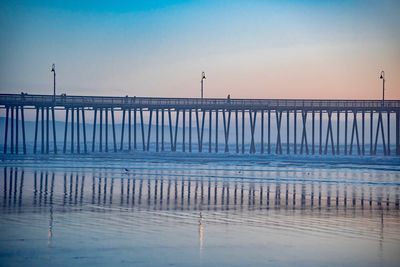 Pier on sea against sky at sunset