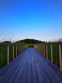 Long wooden footbridge against clear blue sky